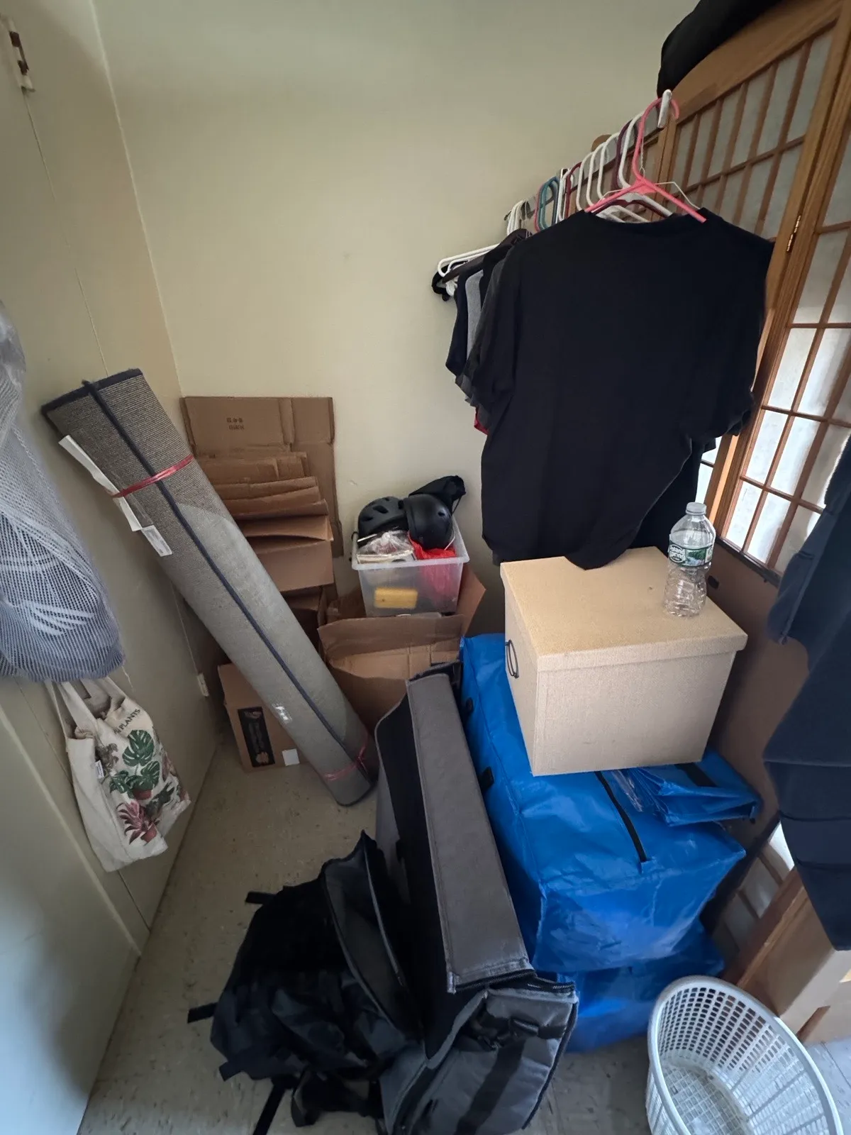 The room — a decade of boxes, Ikea bags, and a rolled-up rug.